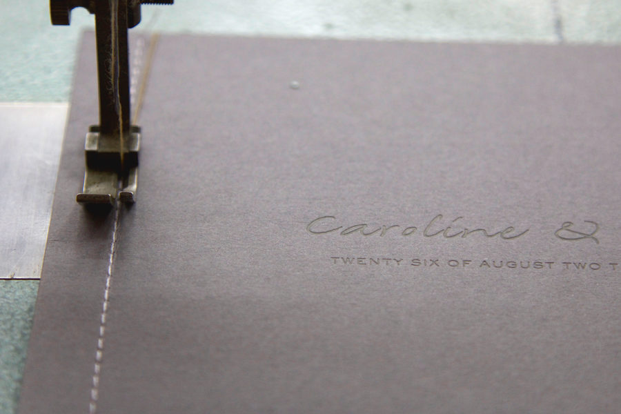Faire-part de mariage relié en couture de fil blanc avec les prénoms et la date en gravure ton sur ton par l'imprimerie Intaglio